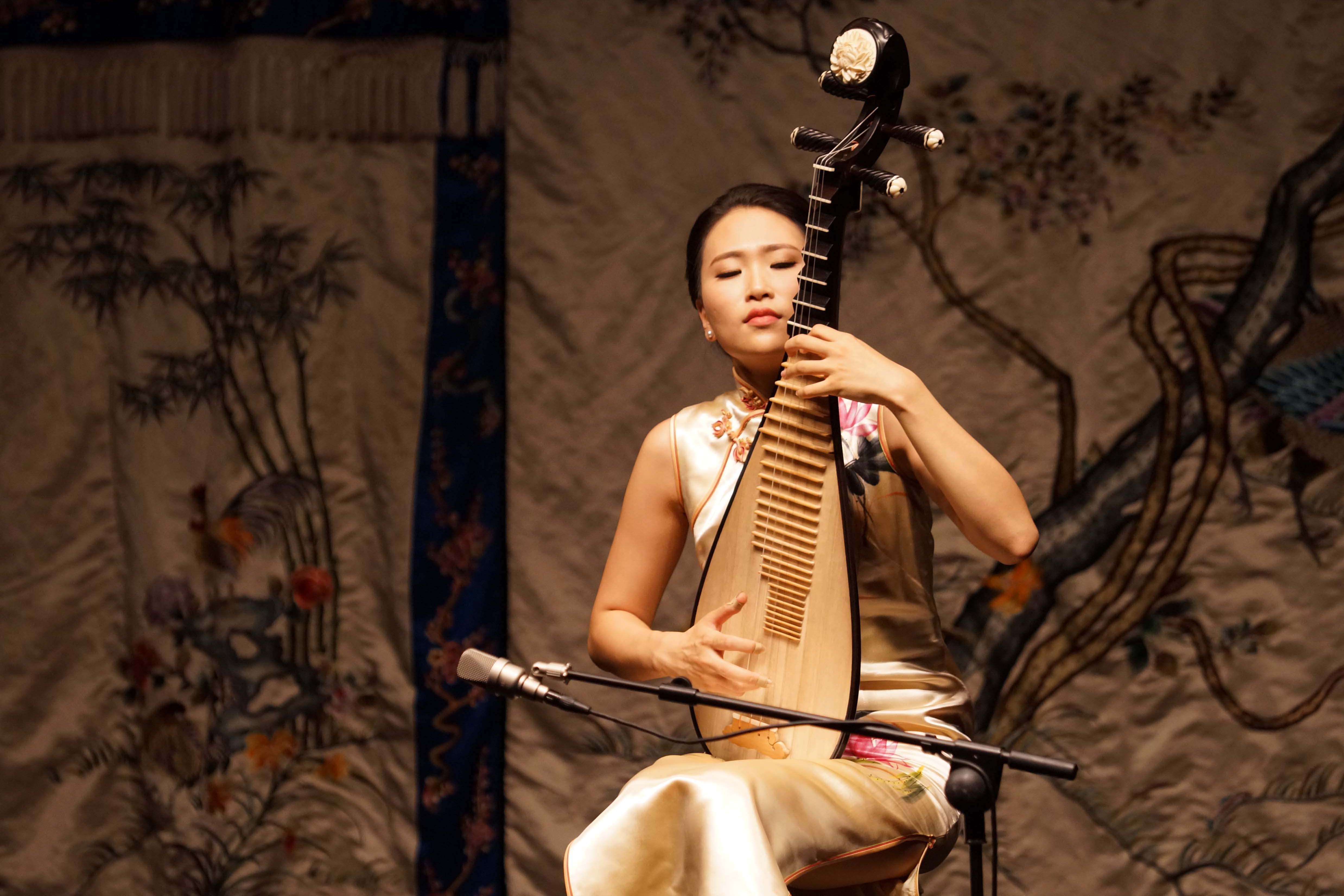 Lucy Zhao performing the pipa in traditional dress during a solo performance 